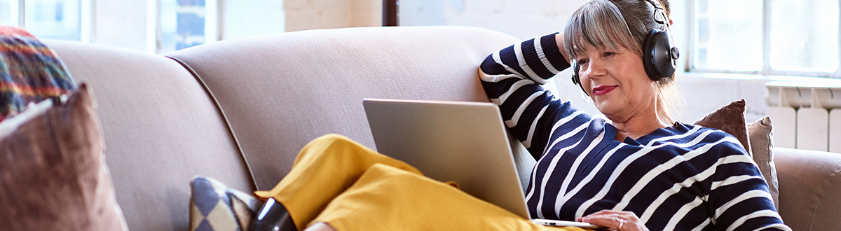 A women relaxing on sofa and listening music via laptop